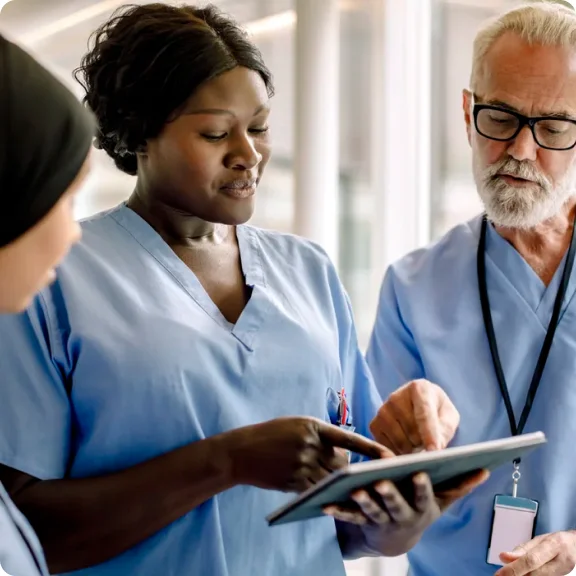 三位醫護人員正在查看平板電腦並進行討論。