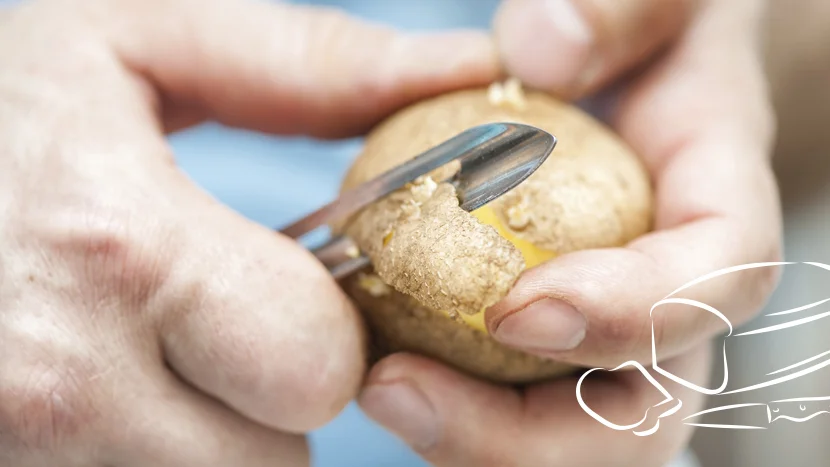 a close-up of a person peeling a potato