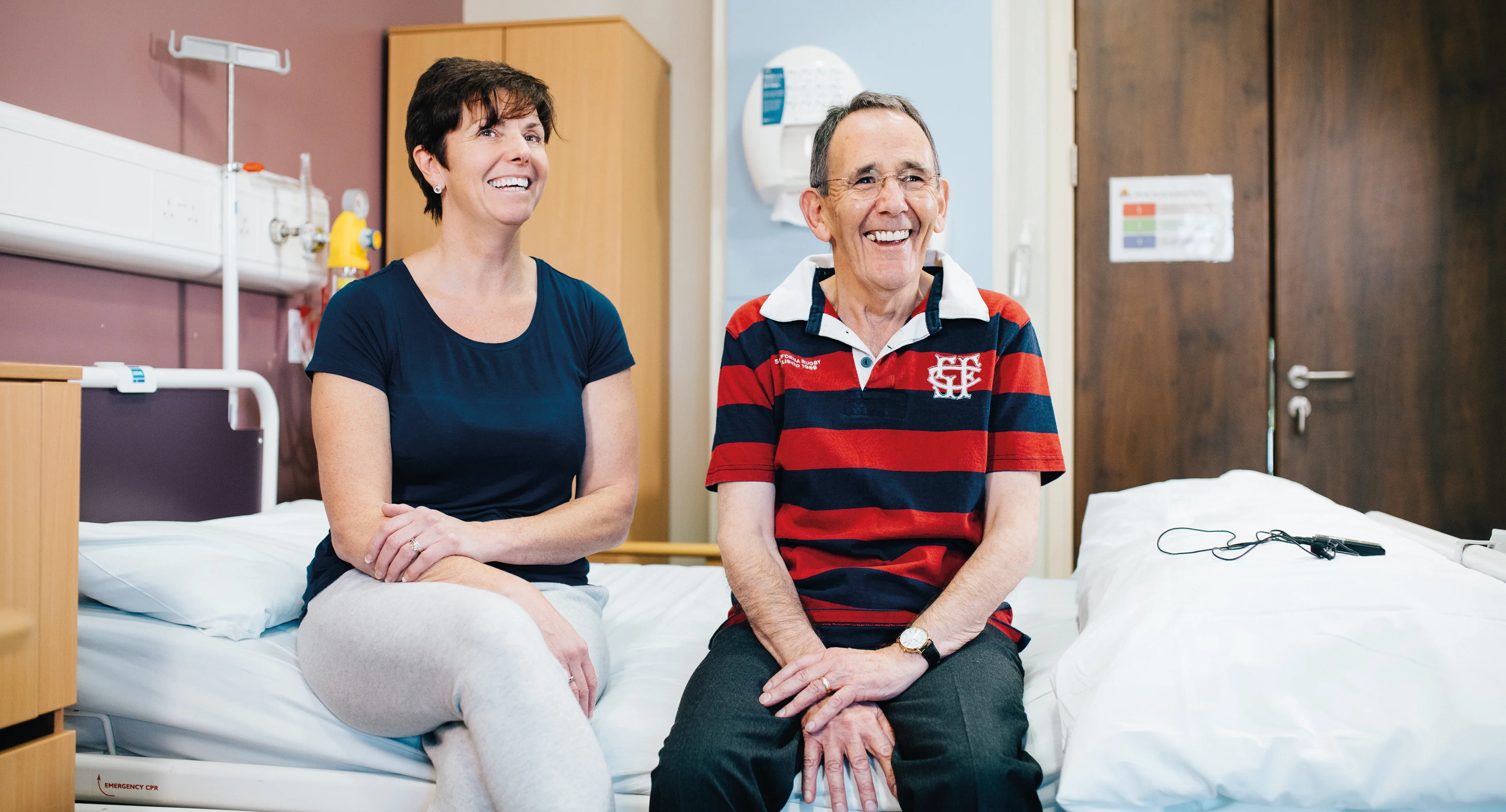 a woman and a man sitting on a hospital bed