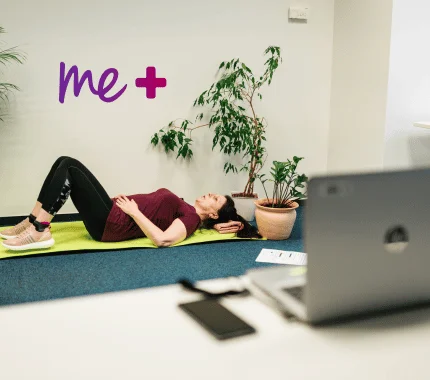 Osoba ležící na podlaze vedle notebooku a rostliny